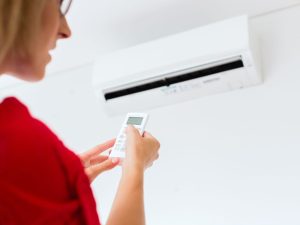 woman holding her air conditioner remote - adjusting the settings