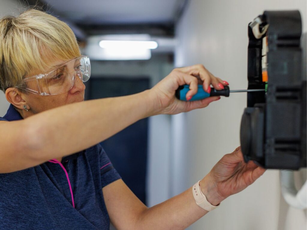 woman holding a screw driver installing an EV charger 